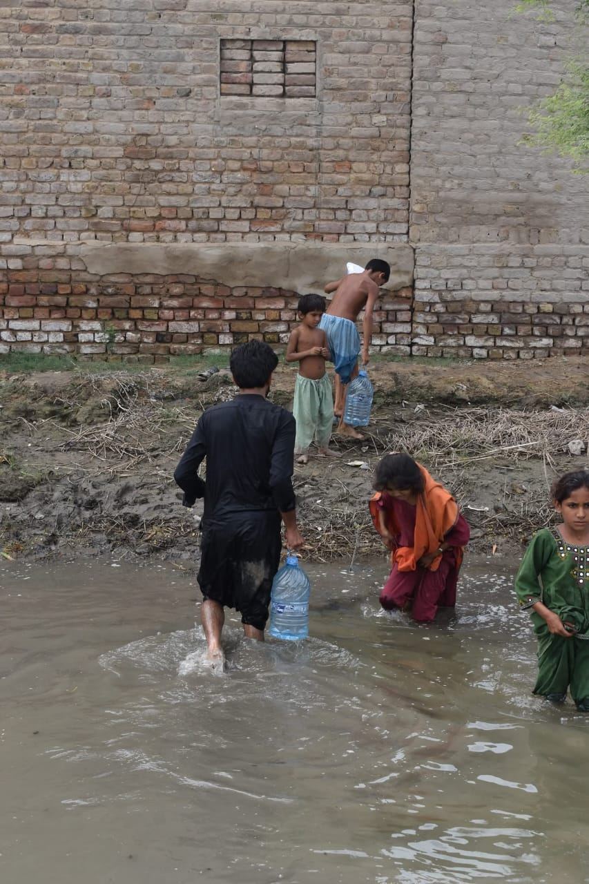 Children crossing flood water to fetch supplies